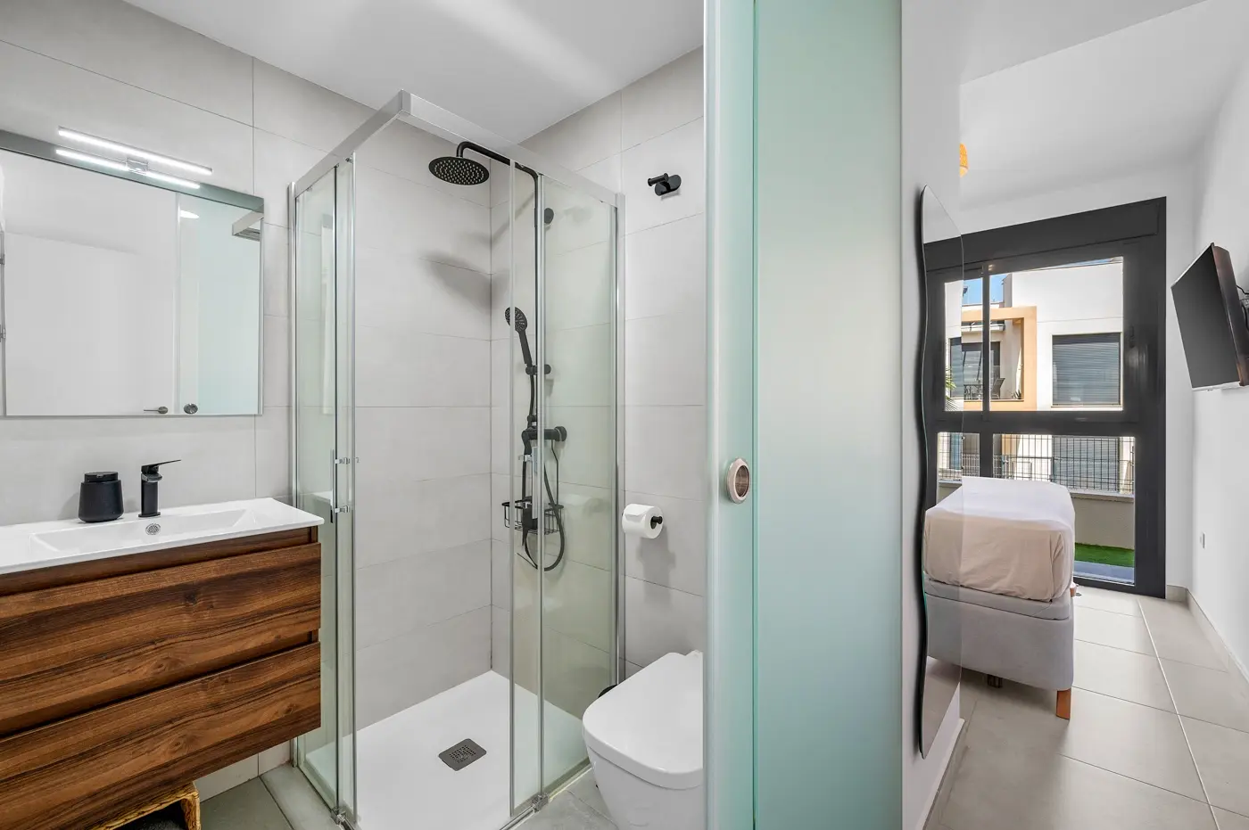 Bathroom with walk-in shower and sliding frosted door opening to the bedroom