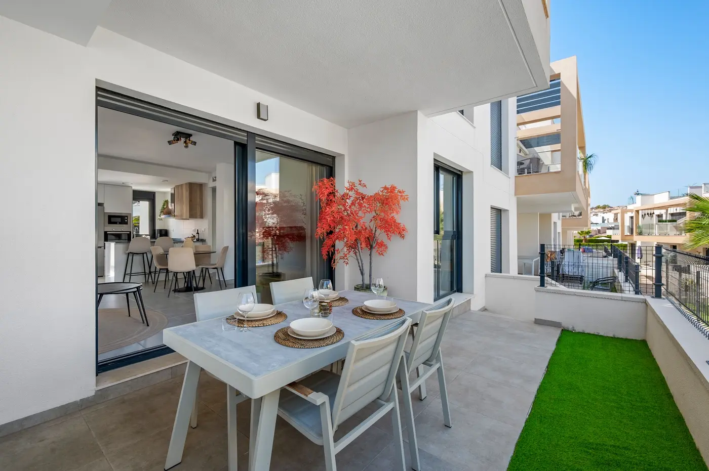 Covered terrace dining table set for four beside sliding doors to the living room