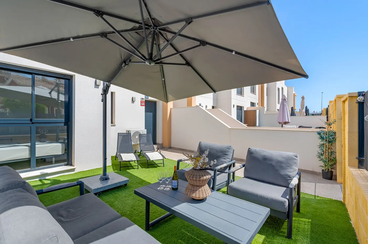 Terrace lounge with grey sofas, coffee table and large parasol