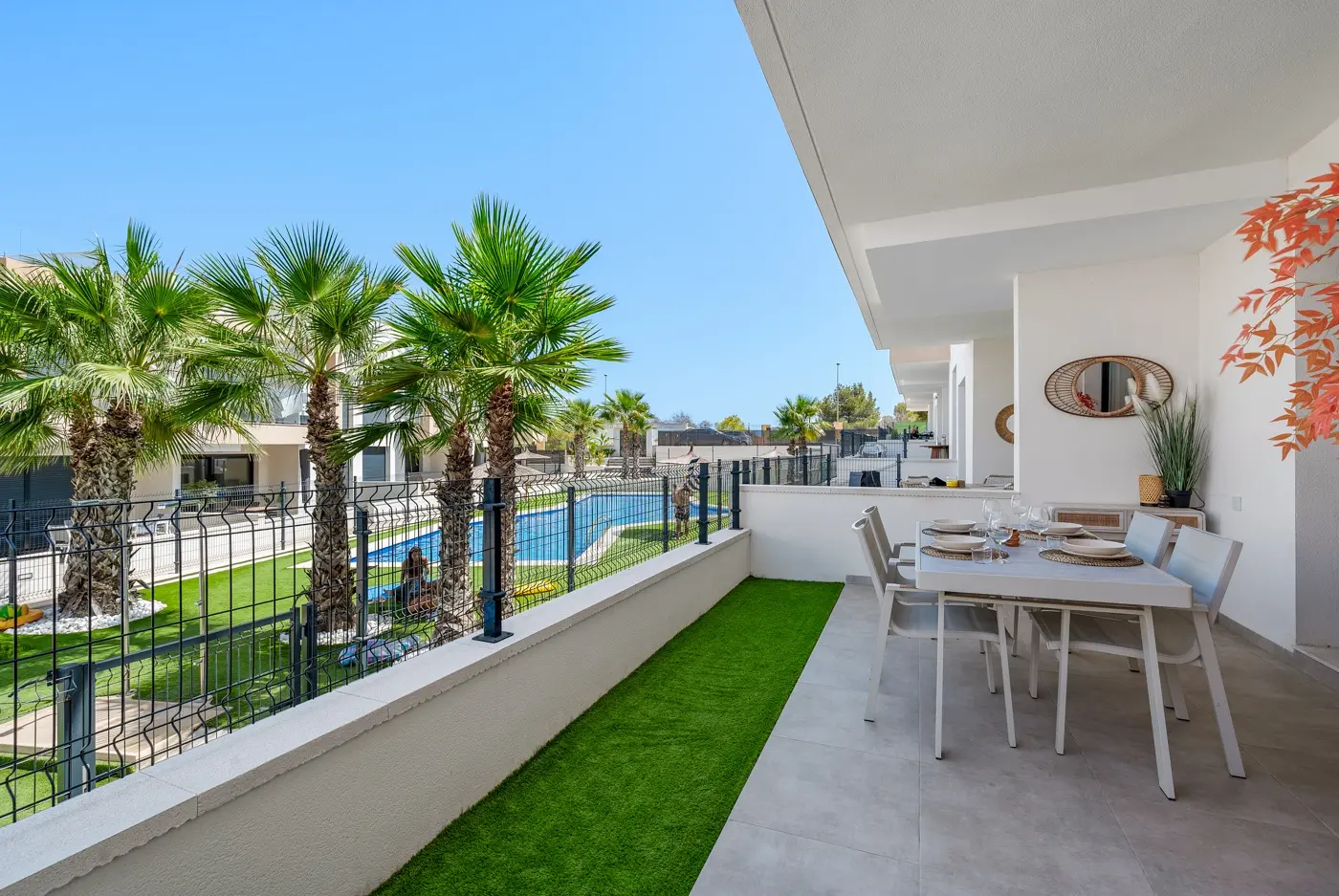 Covered terrace overlooking palm-lined communal gardens and pool