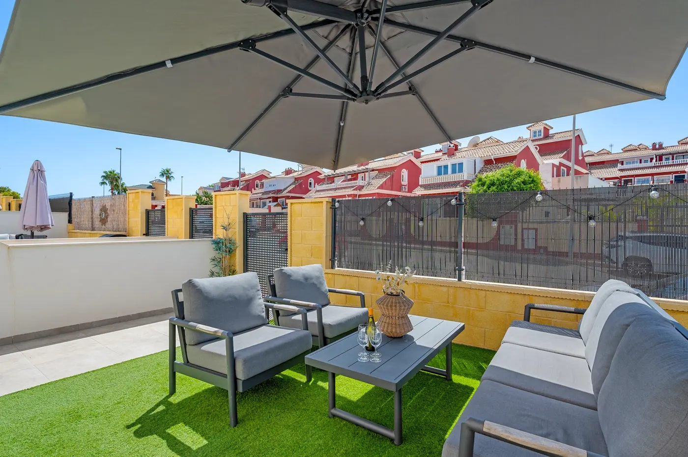 Shaded outdoor seating area on artificial lawn with garden wall