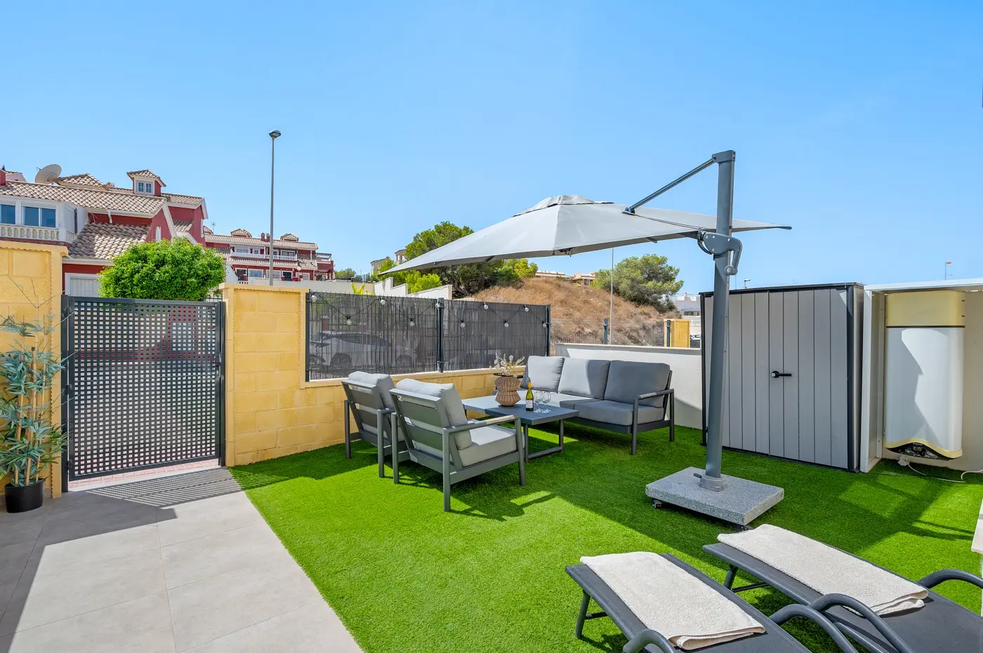 Private terrace garden with artificial lawn, lounge set and parasol